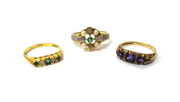 A 9ct gold ring mounted with three circular cut amethysts and with two pairs of small diamonds mounted at intervals, an 18ct gold, emerald and diamond