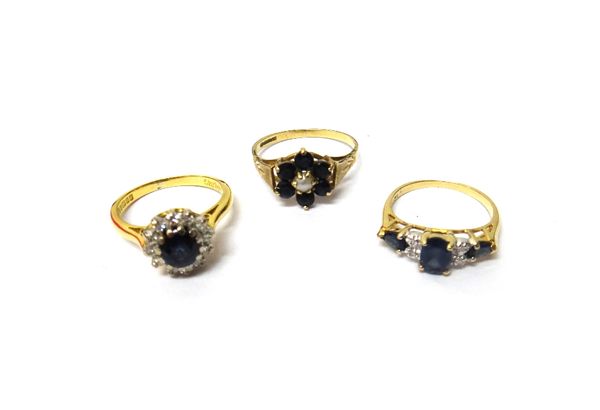 An 18ct gold, sapphire and diamond set cluster ring, claw set with the circular cut sapphire at the centre, in a surround of circular cut diamonds, a