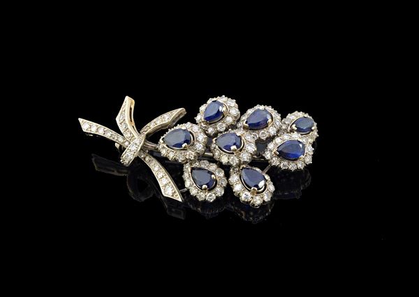 A diamond and sapphire set brooch, designed as a spray, mounted with eight pear shaped sapphires, each with a surround of circular cut diamonds, detai