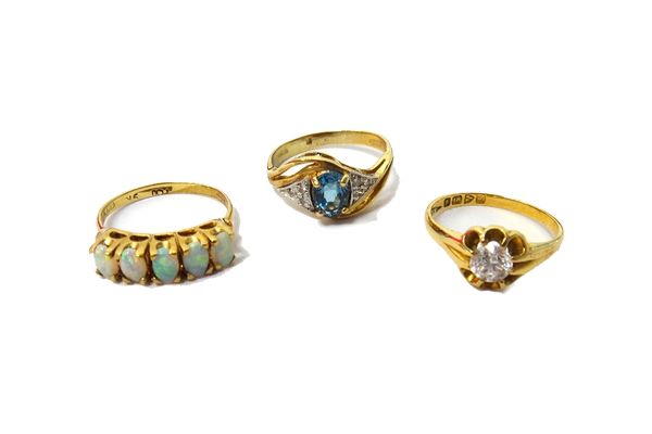 An 18ct gold and colourless gem set solitaire ring, Chester 1918, a 9ct gold, diamond and pale blue gem set ring, in a twist over design and a 9ct gol