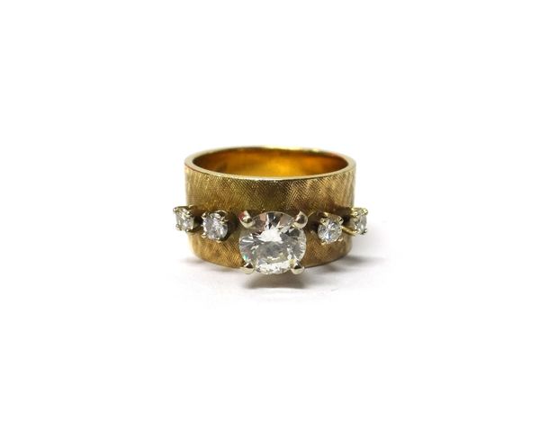 A gold and diamond set band ring, claw set with the principal circular cut diamond at the centre, between two pairs of smaller circular cut diamonds,