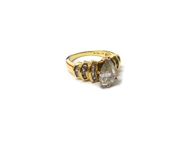 A gold and diamond set ring, claw set with the principal pear shaped diamond at the centre, between diamond set curved stepped shoulders, mounted with