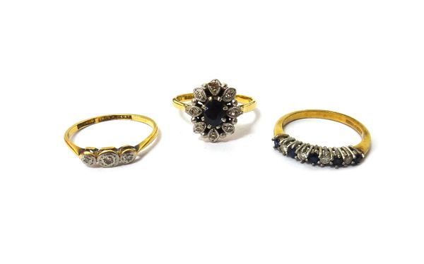 An 18ct gold, sapphire and diamond set nine stone oval cluster ring, a gold and platinum, diamond set three stone ring and a 9ct gold, sapphire and di