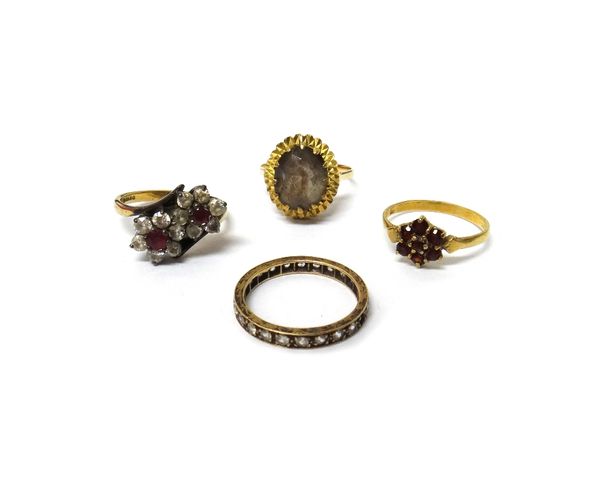 A gold ring, claw set with an oval cut smoky quartz, a 9ct gold and garnet set seven stone cluster ring, a 9ct gold, red and colourless gem set twin c