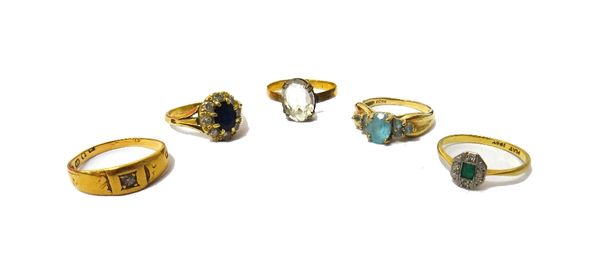 A gold and platinum, emerald and diamond set five stone cluster ring, a gold and pale blue gem set ring, detailed 9 K, a colourless gem set solitaire