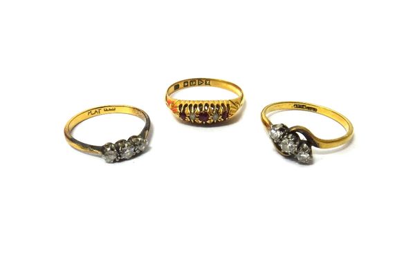 A gold and platinum, diamond set three stone ring, claw set with a row of circular cut diamonds in a crossover design, a gold and platinum, diamond se