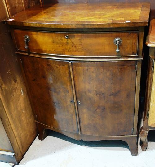 A walnut bowfront side cabinet with single drawer and pair of cupboards.