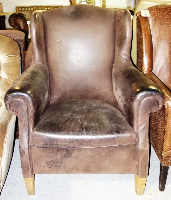 A mahogany brown leather wing armchair.