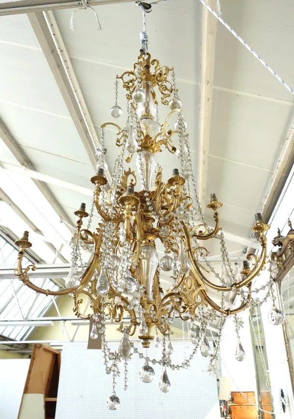 A French twelve branch gilt brass chandelier, early 20th century, the glass stem issuing two graduated tiers of branches, united by chains of glass be