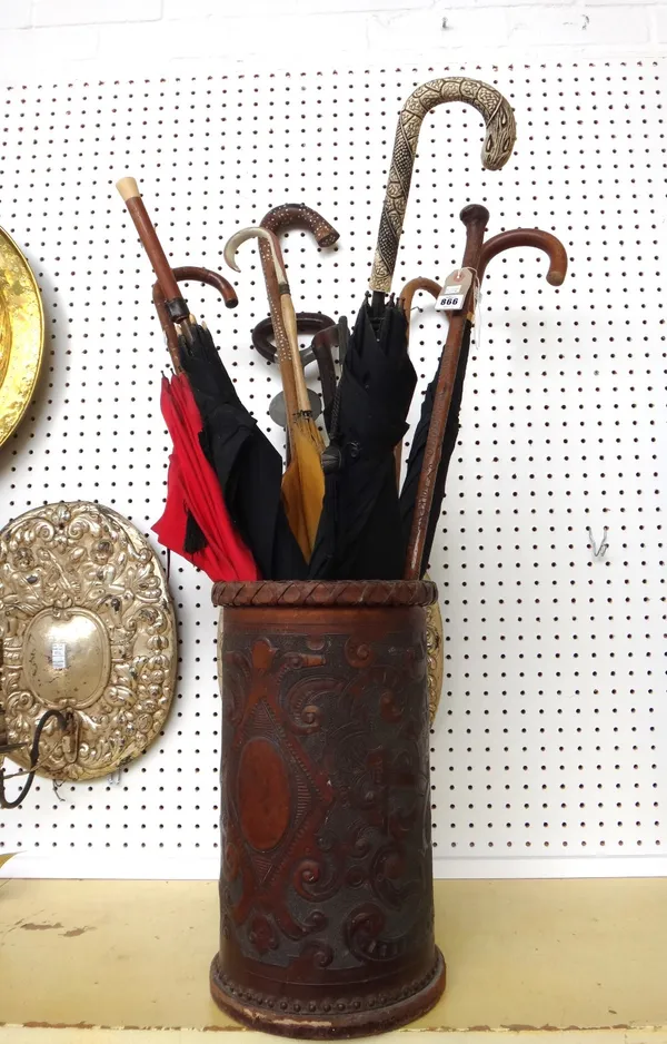 A Victorian embossed leather stick stand and eleven umbrellas and walking sticks, including an umbrella with a gold ferrule, a Victorian carved stick