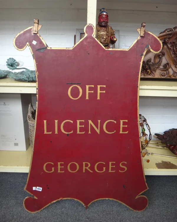 A late 19th century sheet metal hanging sign, gilt lettered 'OFF LICENCE GEORGES' against a burgundy shield shaped ground with a picture of 'Stokescro