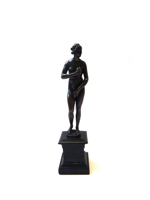 An Italian bronze figure of the Venus de Medici, late 18th century/early 19th century, with shaped base and an ebonised wooden plinth, 19cm high exclu