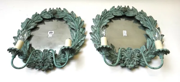 A pair of modern carved wood girandole wall mirrors, each green painted circular wreath issuing two swan neck arms with carved sconces (42cm high) and