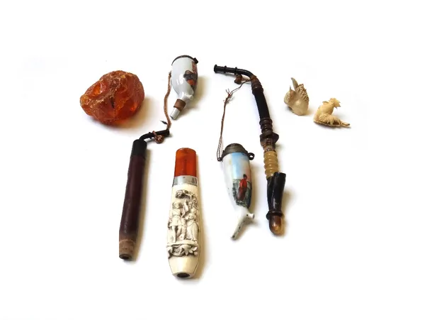 An unusual Meerschaum pipe decorated with carved figures, with an amber coloured mouthpiece, 16cm long, together with a geological amber type specimen