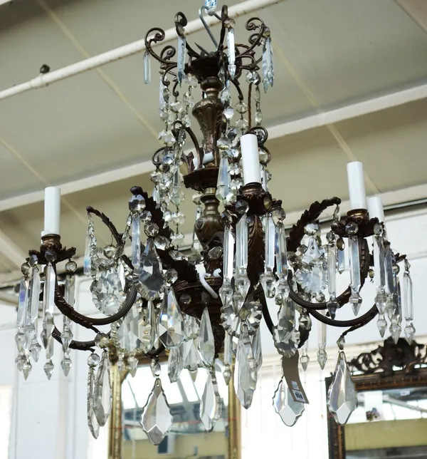 A bronze eight branch chandelier, 20th century, hung with glass drops and prisms over two tiers, the baluster stem issuing eight reeded swan neck arms