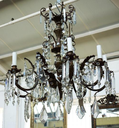 A bronze eight branch chandelier, 20th century, hung with glass drops and prisms over two tiers, the baluster stem issuing eight reeded swan neck arms