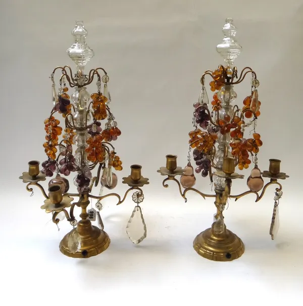 A pair of brass and glass four branch candelabra, mid 20th century, hung with coloured glass grape bunches over three graduated tiers, on a shaped cir