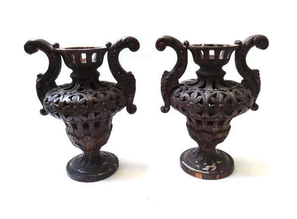 A pair of 17th century style carved and pierced wooden two handled urns, 20th century, each gilt and patinated over a pierced foliate body, 40cm high.