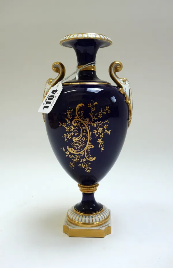 A Royal Worcester two handled vase, circa 1905, painted by Harry Chair with still life flowers against a gilt cobalt blue ground, raised on a pedestal