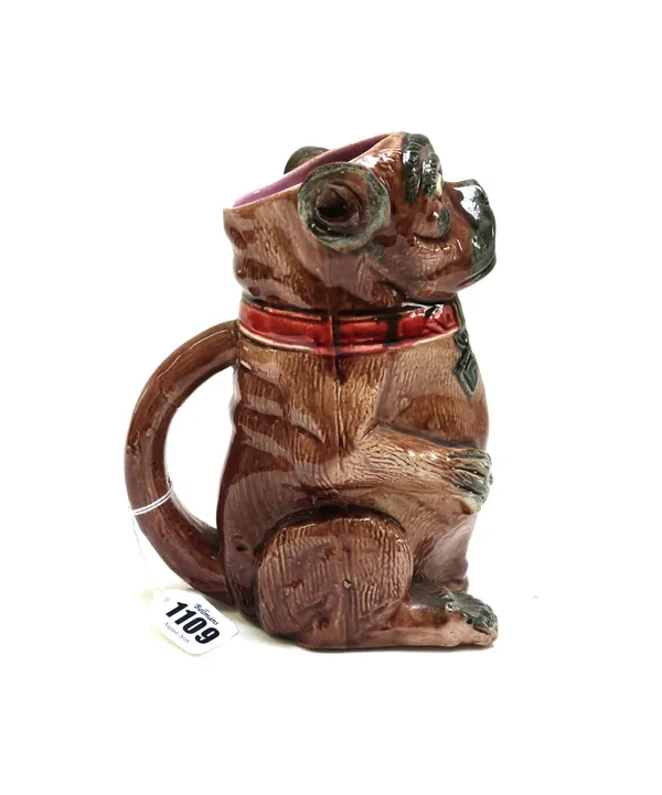 A majolica jug, late 19th century, in the form of a dog seated with open mouth, its tail forming the handle, 18.5cm.high.