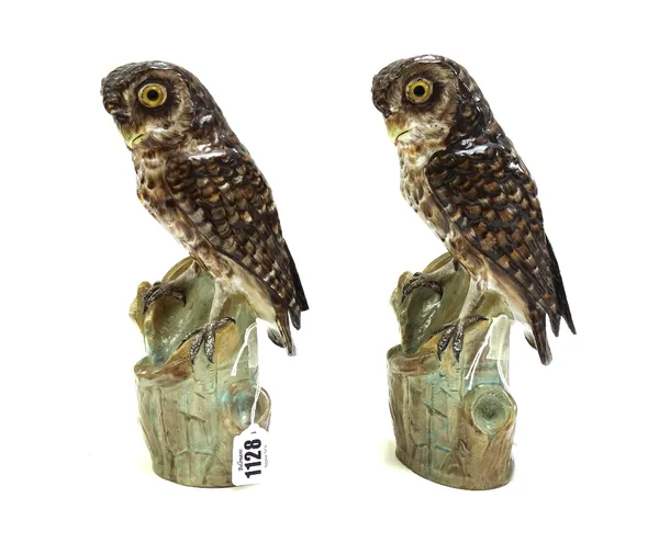 A pair of German porcelain models of owls, early 20th century, each with inset glass eyes modelled atop a tree stump (a.f), 24.5cm high. (2)