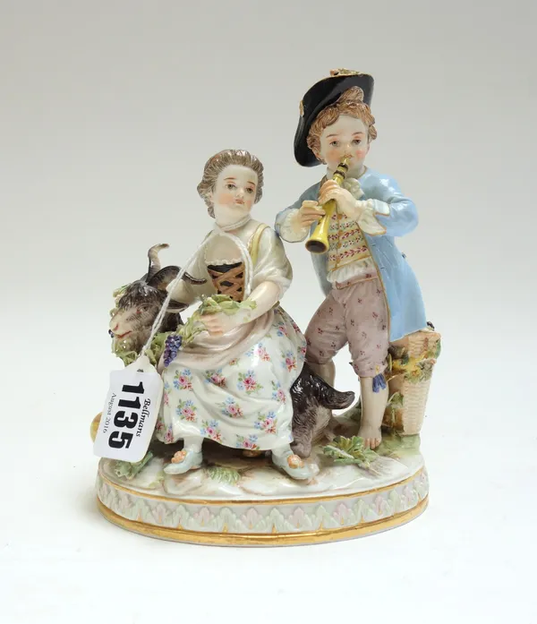 A Meissen porcelain figure group, circa 1900, modelled as a shepherd and shepherdess atop a goat, on an oval naturalistic base, with blue crossed swor