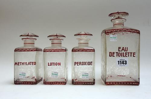 A set of four ruby flashed etched glass toiletry bottles and stoppers, comprising; 'Eau de toilette', 20.5cm high, and three smaller matching, 'Lotion