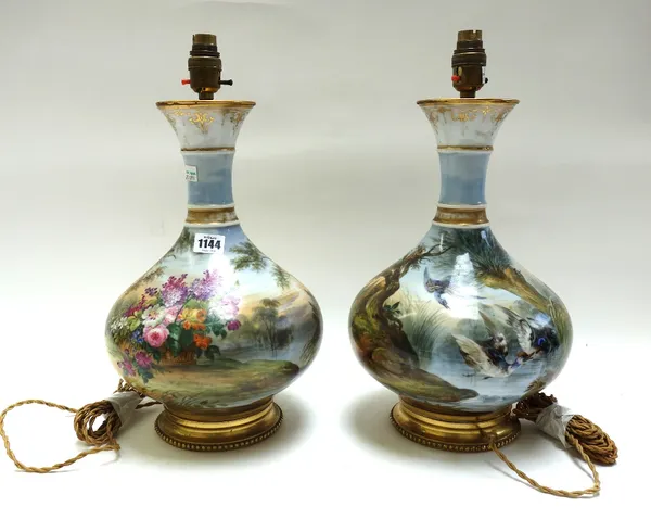 A pair of French porcelain vase table lamps, circa 1900, each painted with wild birds against a naturalistic lake land ground, on a gilt brass circula