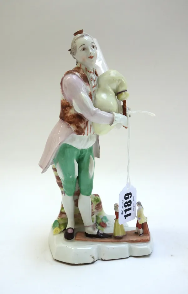 A Vienna figure of a bagpipe player, circa 1765, with blue shield mark, puce painter's mark '16', modelled standing before a tree trunk with puppets a