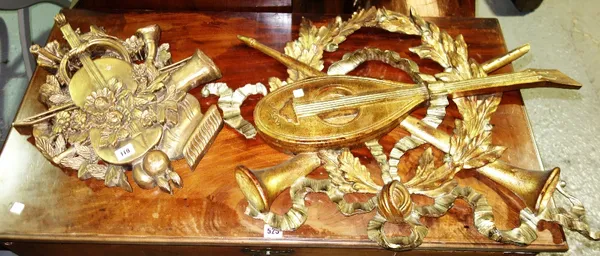 A similar pair of moulded gilt wall mounted decorations, depicting musical instruments, ribbons and swags, (2).