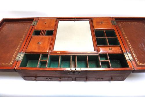 An early 19th century mahogany travelling toilet box, the pair of inlaid lift tops enclosing a fitted interior, over a pair of drawers, 60cm wide.