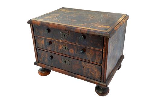 An oyster veneered table top cabinet with three long graduated drawers, on bun feet, 33cm wide x 23cm deep x 25cm high.    Item 58  Illustrated