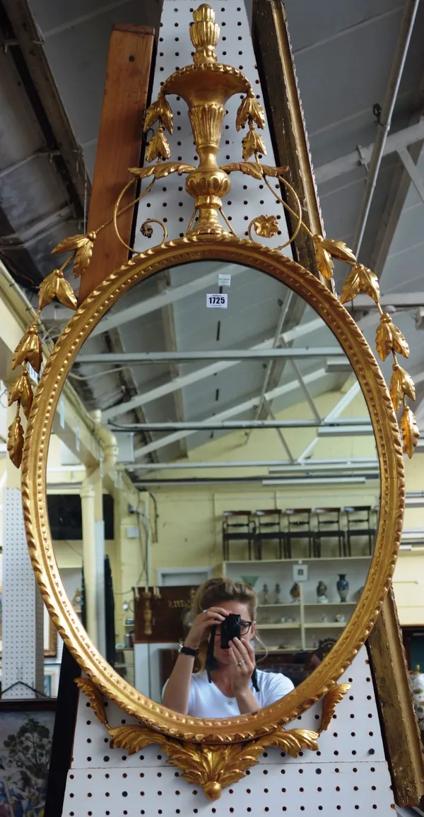 A 19th century gilt framed oval wall mirror of Adams design, with urn finial over leaf chased oval frame, 65cm wide x 125cm high