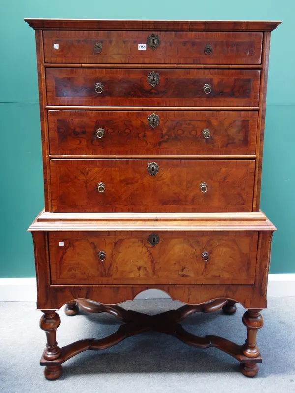 A William and Mary figured walnut chest on stand, the four long feather banded graduated drawers over a single drawer base, on turned supports united