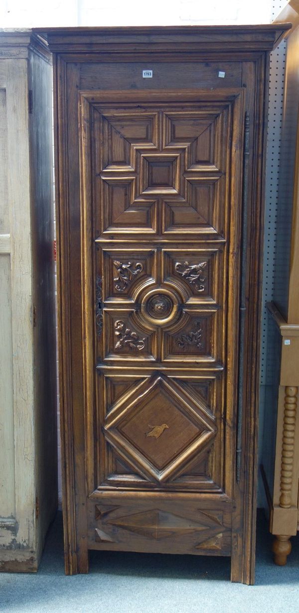 An early 19th century walnut and oak armoire, with carved single door on block feet, 84cm wide x 196cm high.