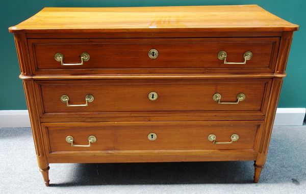 An early 19th century French walnut three drawer commode with fluted rounded corners on tapering turned supports, 132cm wide.