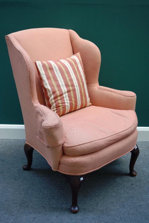 A George I style wing back armchair, on shell capped cabriole supports.