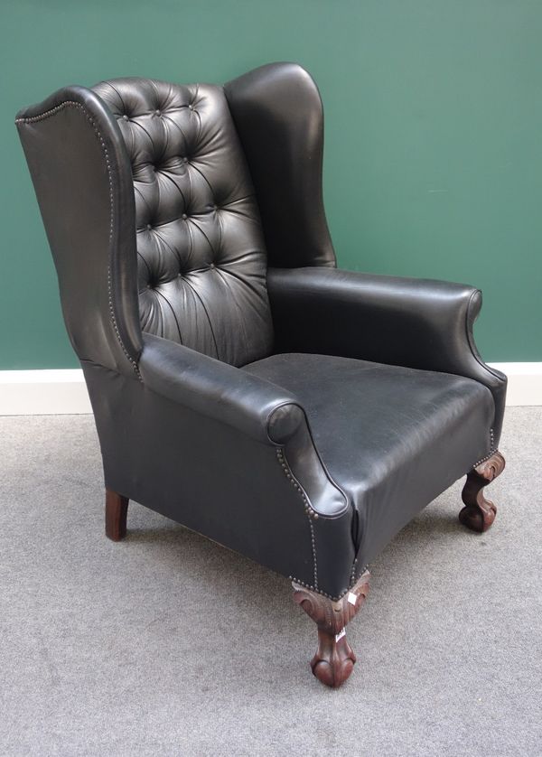 An 18th century style black leather upholstered wing back chair, on mahogany claw and ball supports.