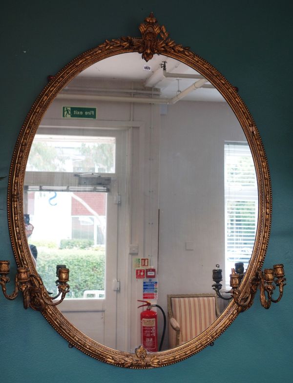 A large Victorian oval gilt framed wall mirror, mounted with a pair of triple wall sconces, 117cm wide x 142cm high.