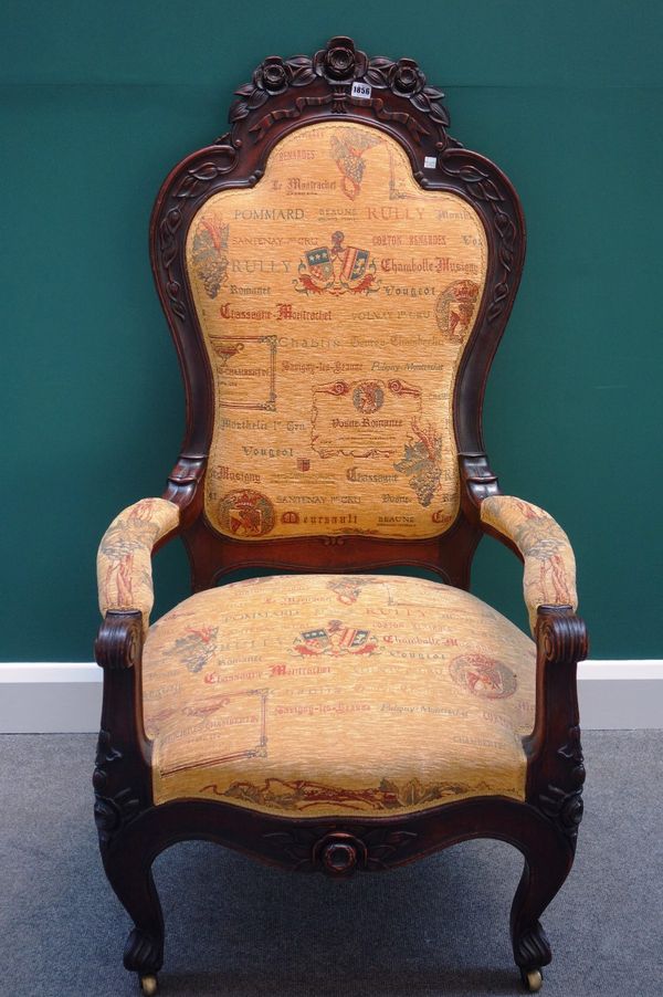 A Victorian carved mahogany framed open arm easy armchair, the upholstery bearing names of French wine regions.