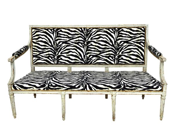 A Louis XVI grey painted canape, with semi-padded open arms, straight front seat, on fluted turned supports, later upholstered in zebra print, 157cm w