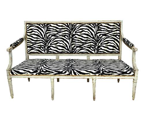 A Louis XVI grey painted canape, with semi-padded open arms, straight front seat, on fluted turned supports, later upholstered in zebra print, 157cm w