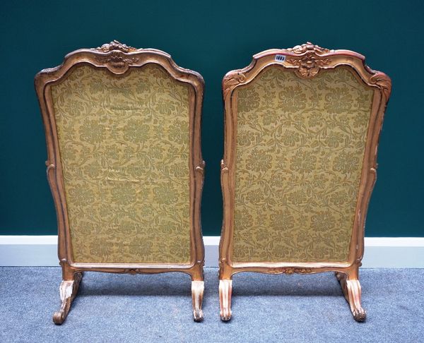 A pair of Victorian rococo revival gilt framed fire screens, on scroll downswept supports, 54cm wide x 100cm high.