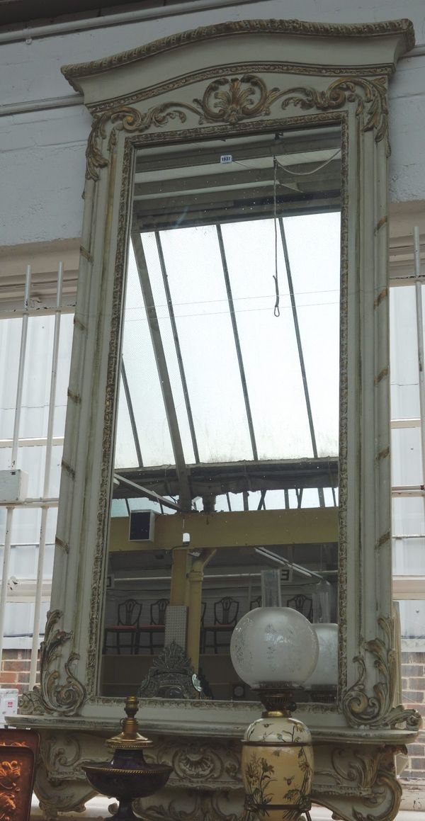 A large parcel gilt grey painted wall mirror, with opposing 'C' scroll frieze, over rectangular plate and serpentine lower shelf, 103cm wide x 217cm h