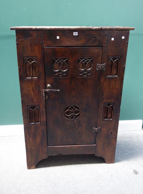A 16th century style stained elm aumbry, with single door and Gothic carved linen backed pierced decoration, on slab end supports, 93cm wide x 134cm h