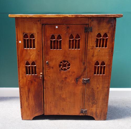 A 16th century style stained elm aumbry, with single door and Gothic carved linen backed pierced decoration, on slab end supports, 114cm wide x 123cm