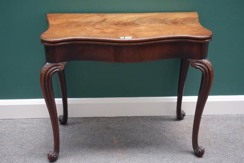A mid 18th century mahogany card table, with serpentine foldover top and concertina action, on channelled cabriole supports, 91cm wide.