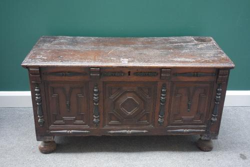 A 17th century oak coffer, the plank top over a geometric moulded and split bobbin mounted triple panel front, on bun feet, 126cm wide.