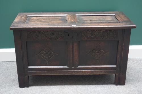 An 18th century oak coffer, with double panel top over carved double panel front, on stile feet, 101cm wide.