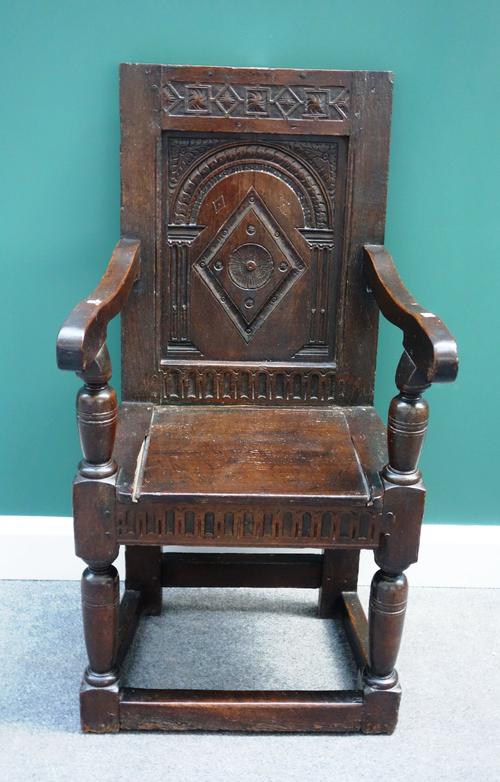 A 17th century and later oak Wainscot chair, with carved panel back, on turned supports, united by perimeter stretcher.